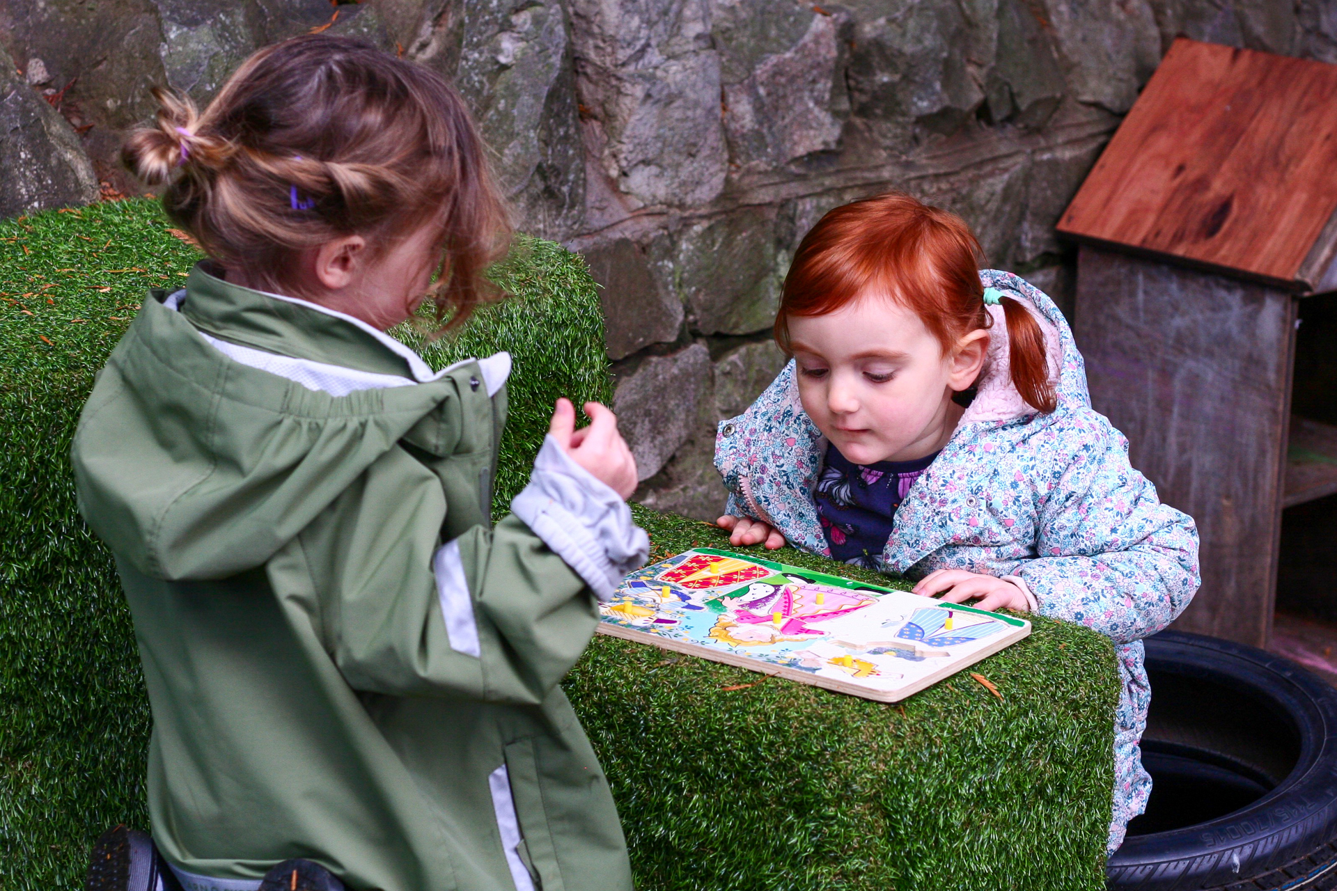 Kindergarten playing with jigsaw in garden
